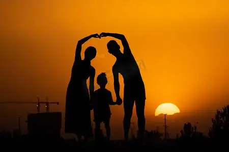 人像剪影夕阳一家三口夕阳下拉孩子手比心摄影图配图
