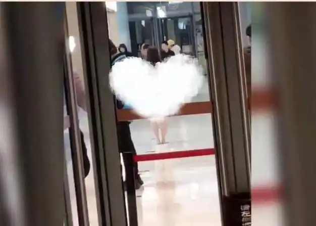 不穿衣服站立在商场通道中,一会儿捂着脸向商场内的其他行人靠近过去