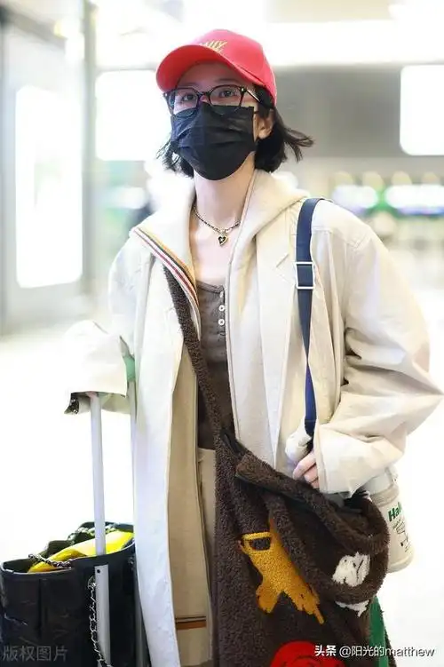 周雨彤穿长款连帽大衣搭休闲裤现身机场红色棒球帽亮眼吸睛