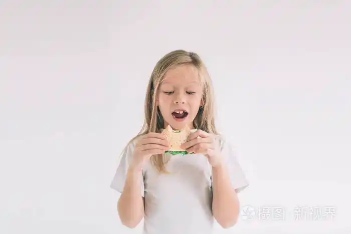 孩子拿着一块汉堡包孩子吃快餐不是有用的食物非常饿的婴儿女孩在白色