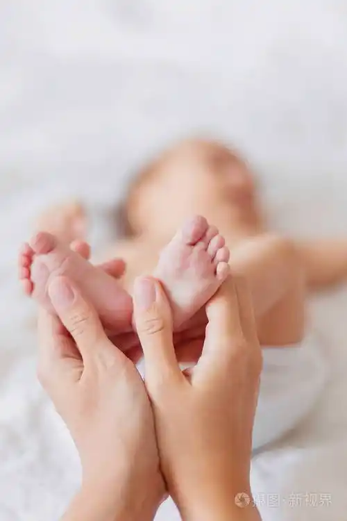 母亲抱着刚出生的婴儿赤裸的双脚在女人的手的小脚舒适的上午在家