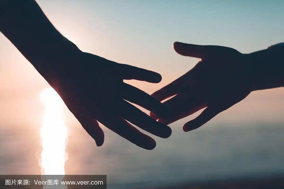 一对手伸向天空和大海背景上的剪影.