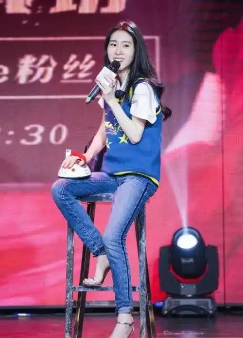 张碧晨身穿一件蓝色的上衣,搭配一件蓝色的牛仔长裤,脚踩一双银色的