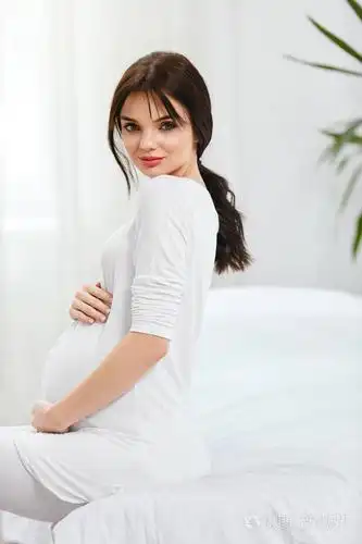 孕妇美丽快乐的孕妇肚子坐在室内的床上决议草案