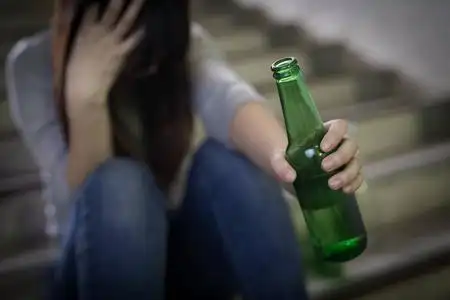 抑郁的妇女感到心烦与酗酒问题和坐在地下醉醺醺的酒鬼女人喝醉了