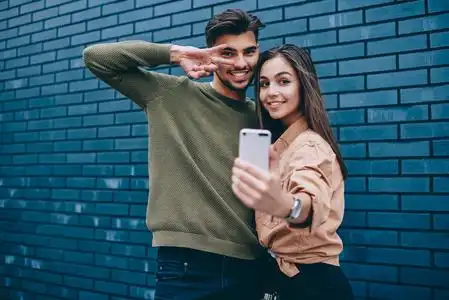 一对快乐的时髦情侣在智能手机摄像头上合影留念,男女青少年穿着休闲