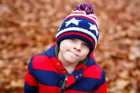 冬季童装幸福可爱的小男孩的肖像与秋季叶背景在五颜六色的衣服.