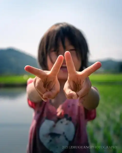 田野守望-童真微笑:不经意的瞬间,拍下了女孩双手比耶的照片,正好对焦