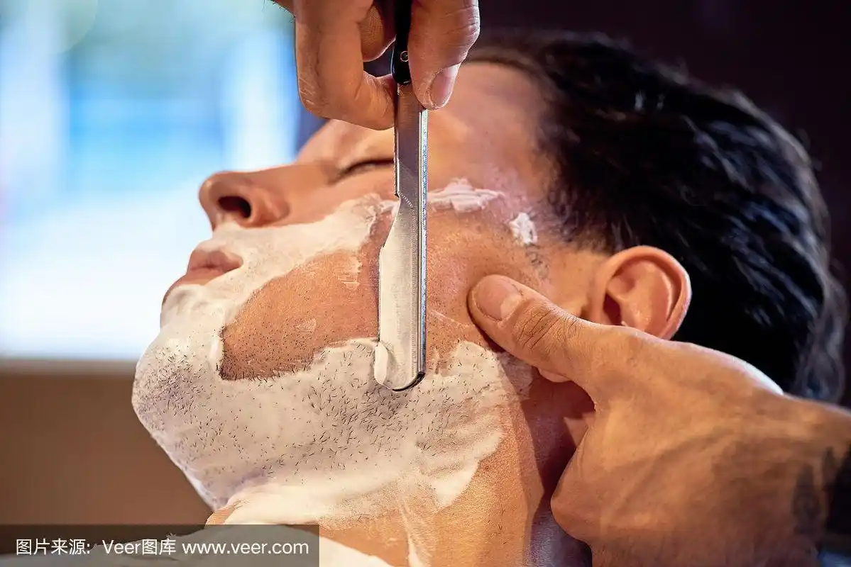 在理发店剃胡子的过程.师傅让客户用老式直刮胡刀刮胡子.