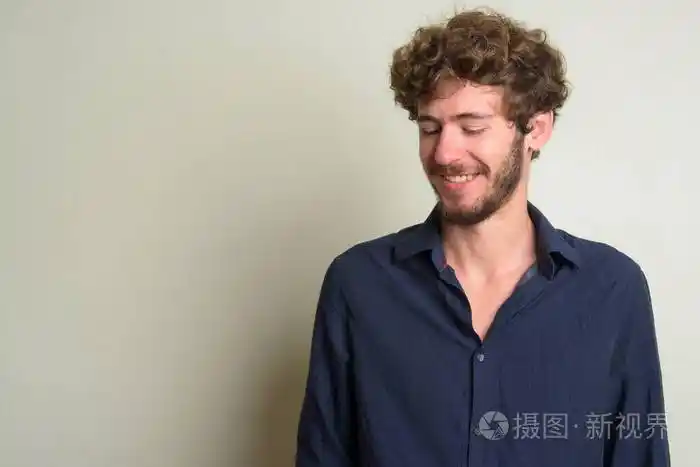 快乐的年轻的留着卷发的商人低头思考着