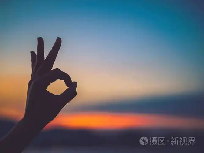特写和剪影的女人手做 ok 手势在日落背景.希望理念