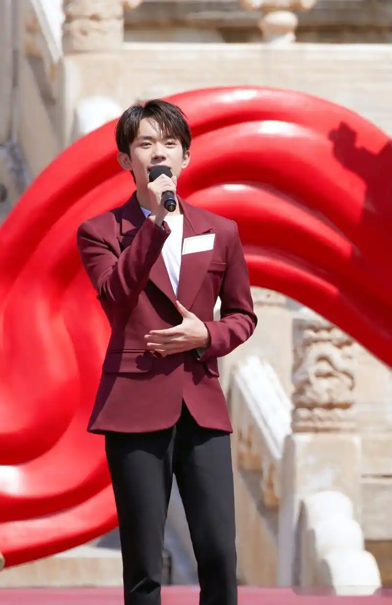 易烊千玺身着酒红色西装,献唱《我们都是追梦人》,洋溢青春风采.