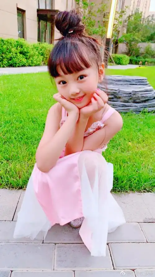 扎起丸子头,换上粉色连衣裙的小山竹,双手托腮对镜卖萌,美得像从童话