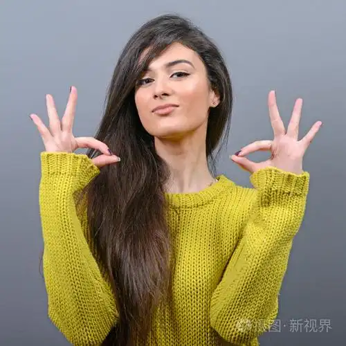 幸福的女人,显示 ok 的手势,在灰色背景下的肖像