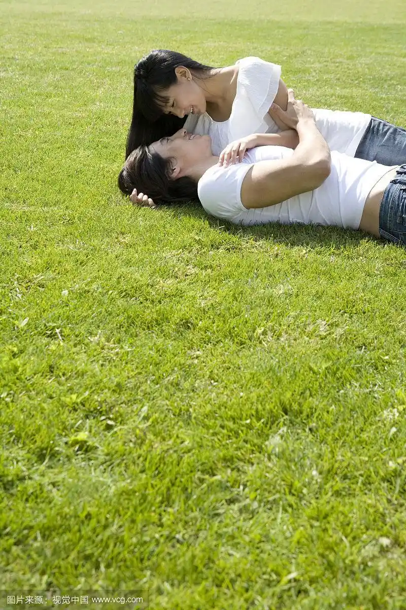 在草地上亲密相拥的情侣